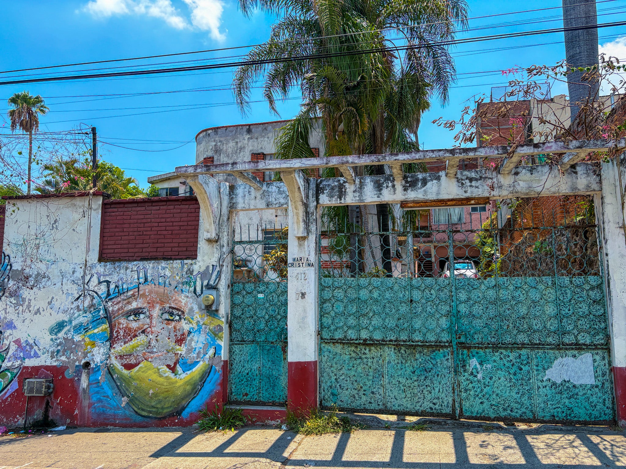 Mural on a wall with a blue sky and palm trees in the background. Art entrance shopping Mexico.