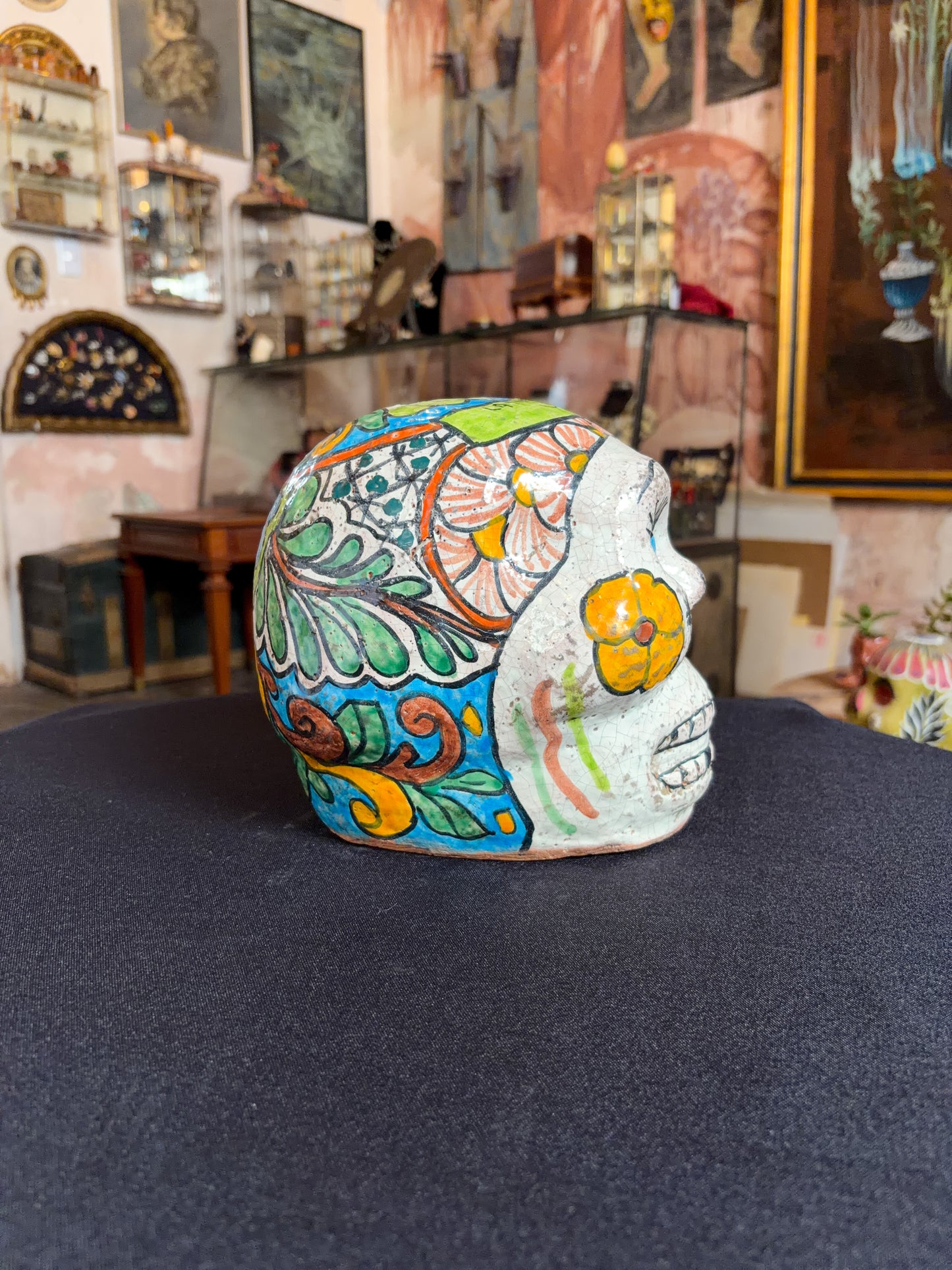 Handcrafted glazed clay skull ornament, Puebla Mexican folk art, left side, blue scroll and leaf pattern